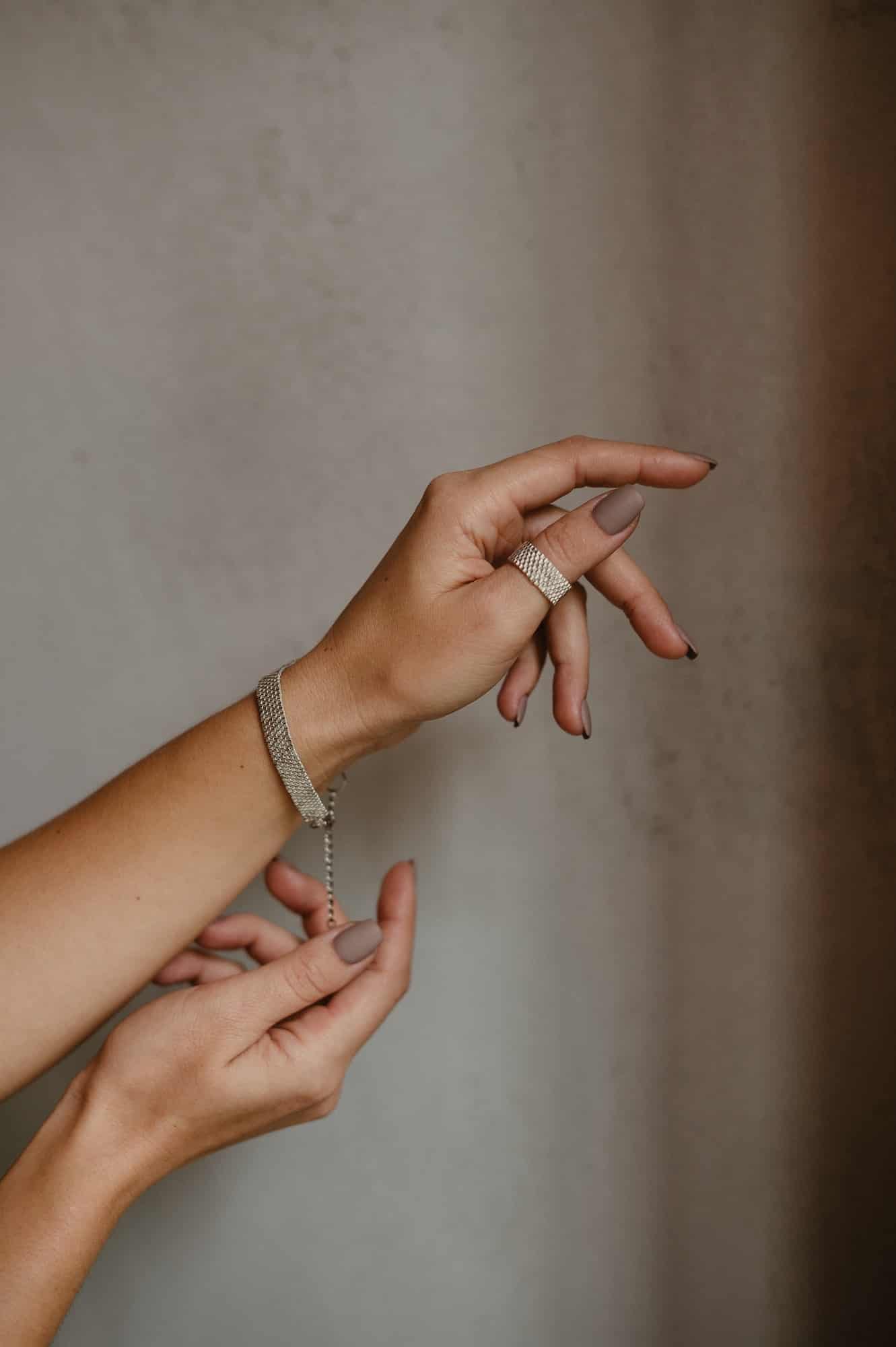 hands on gray background with handmade jewelry